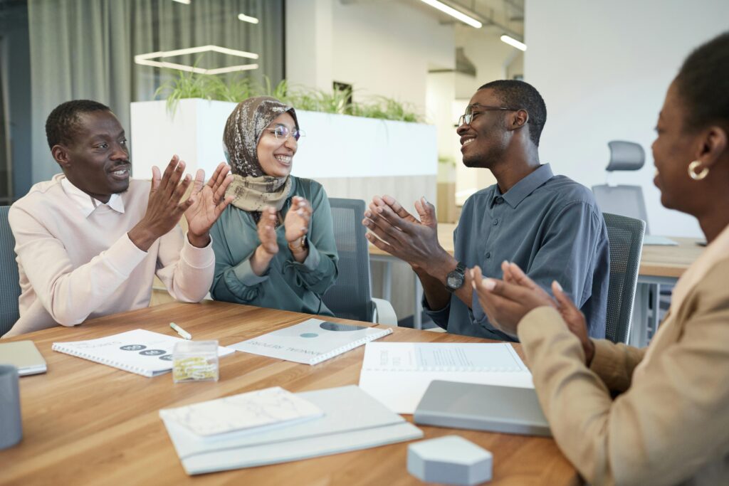A multicultural group of professionals engage in a positive office meeting showing teamwork and support.